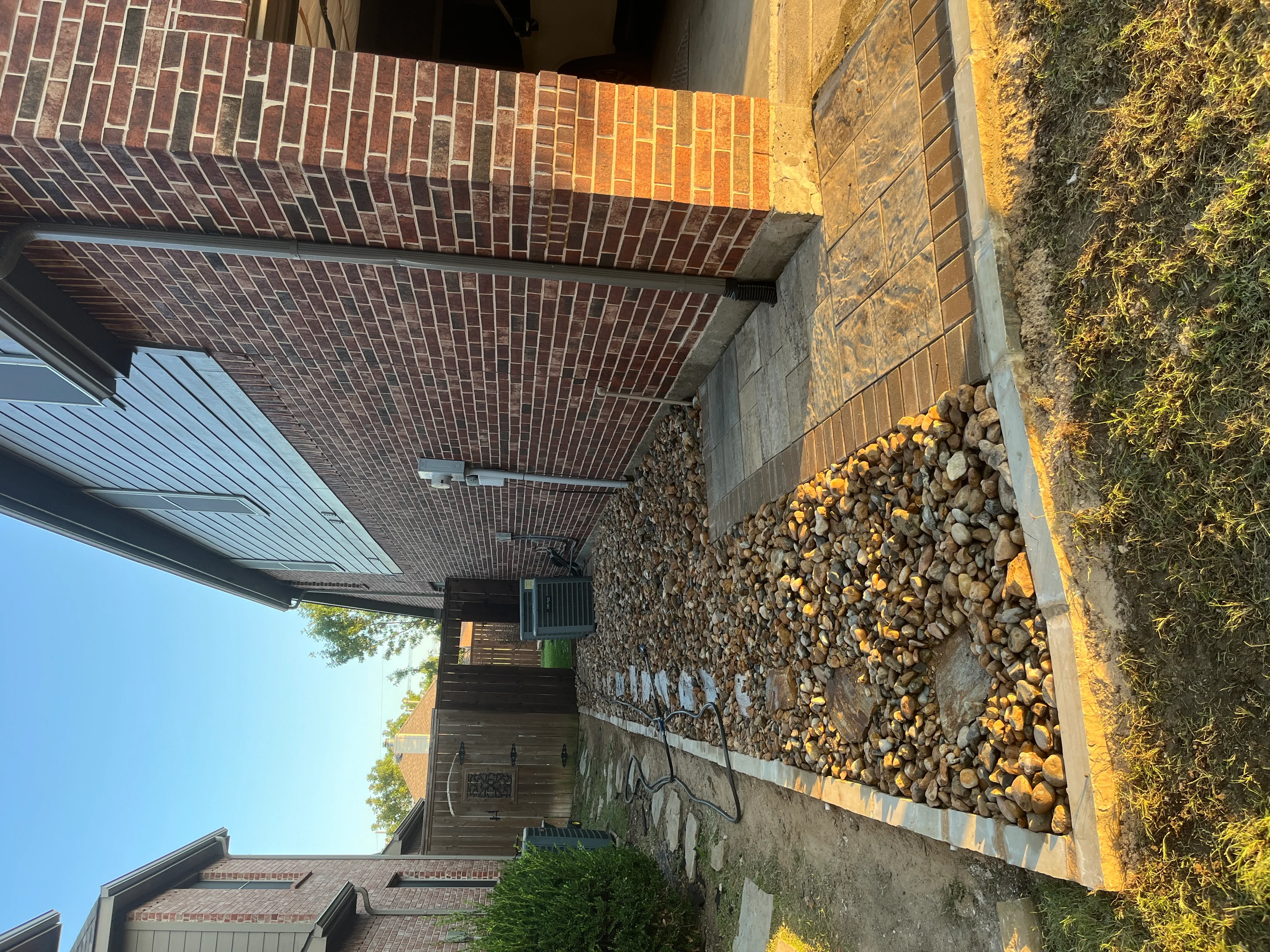 Herringbone brick paver driveway with stacked stone and river rock retaining wall