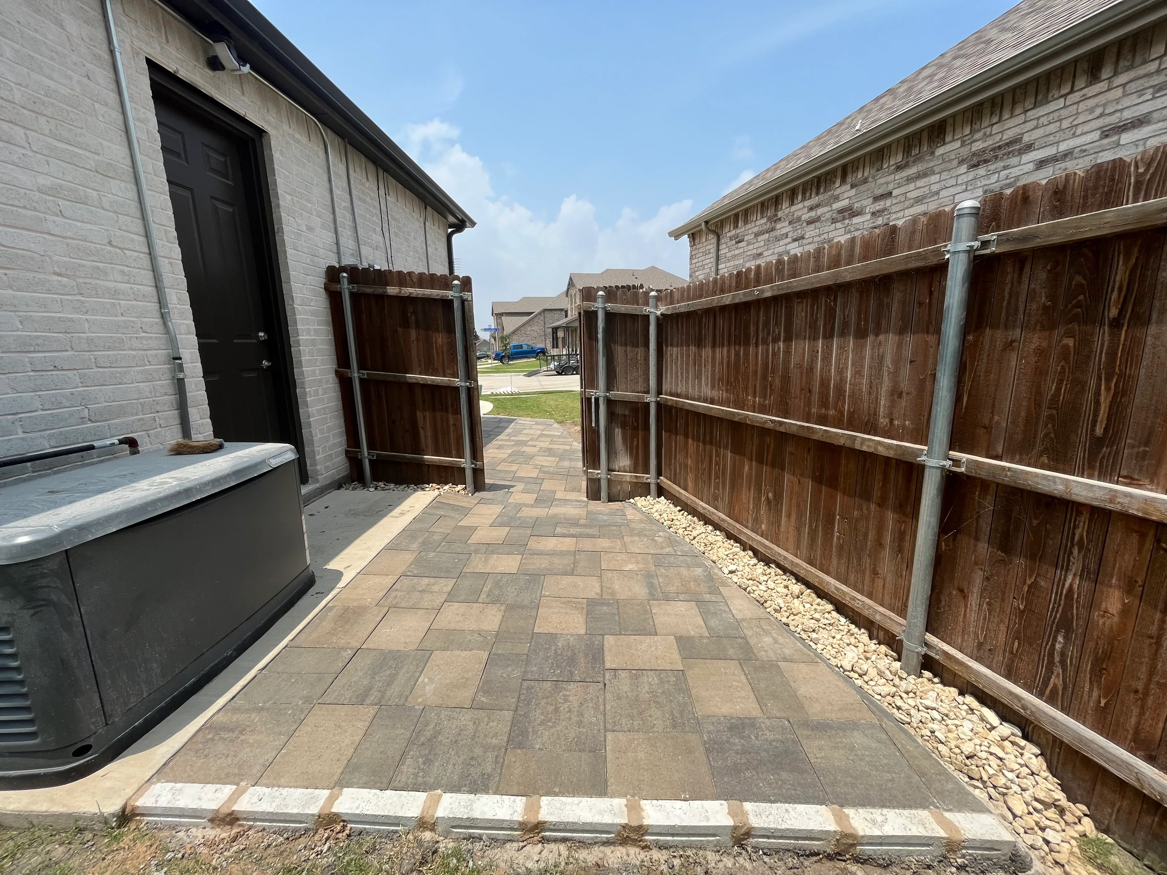 Multi-toned concrete paver patio with running bond pattern and new wood privacy fence with metal posts