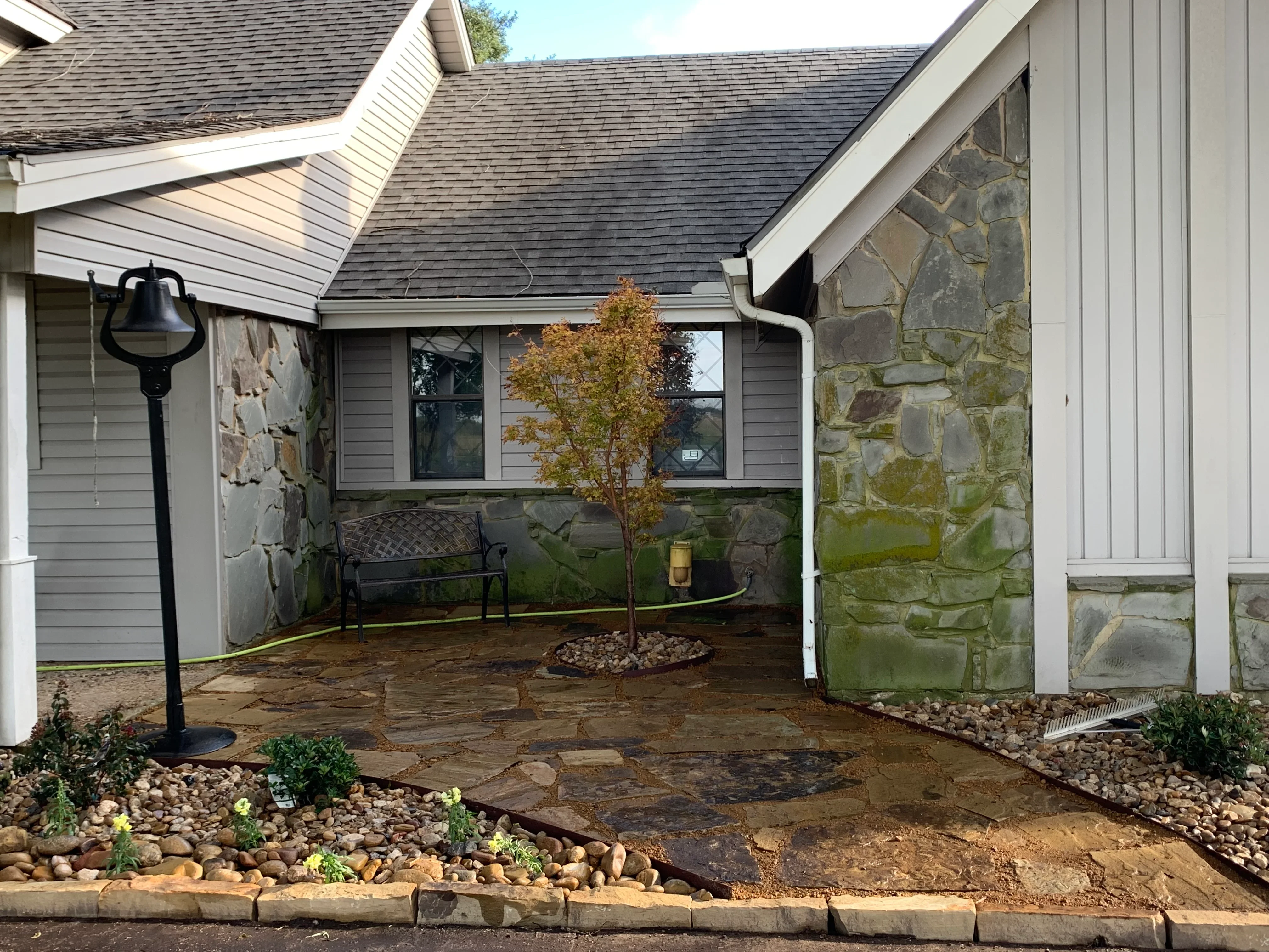 Stone patio with flagstone, river rock borders, and landscape lighting in courtyard setting