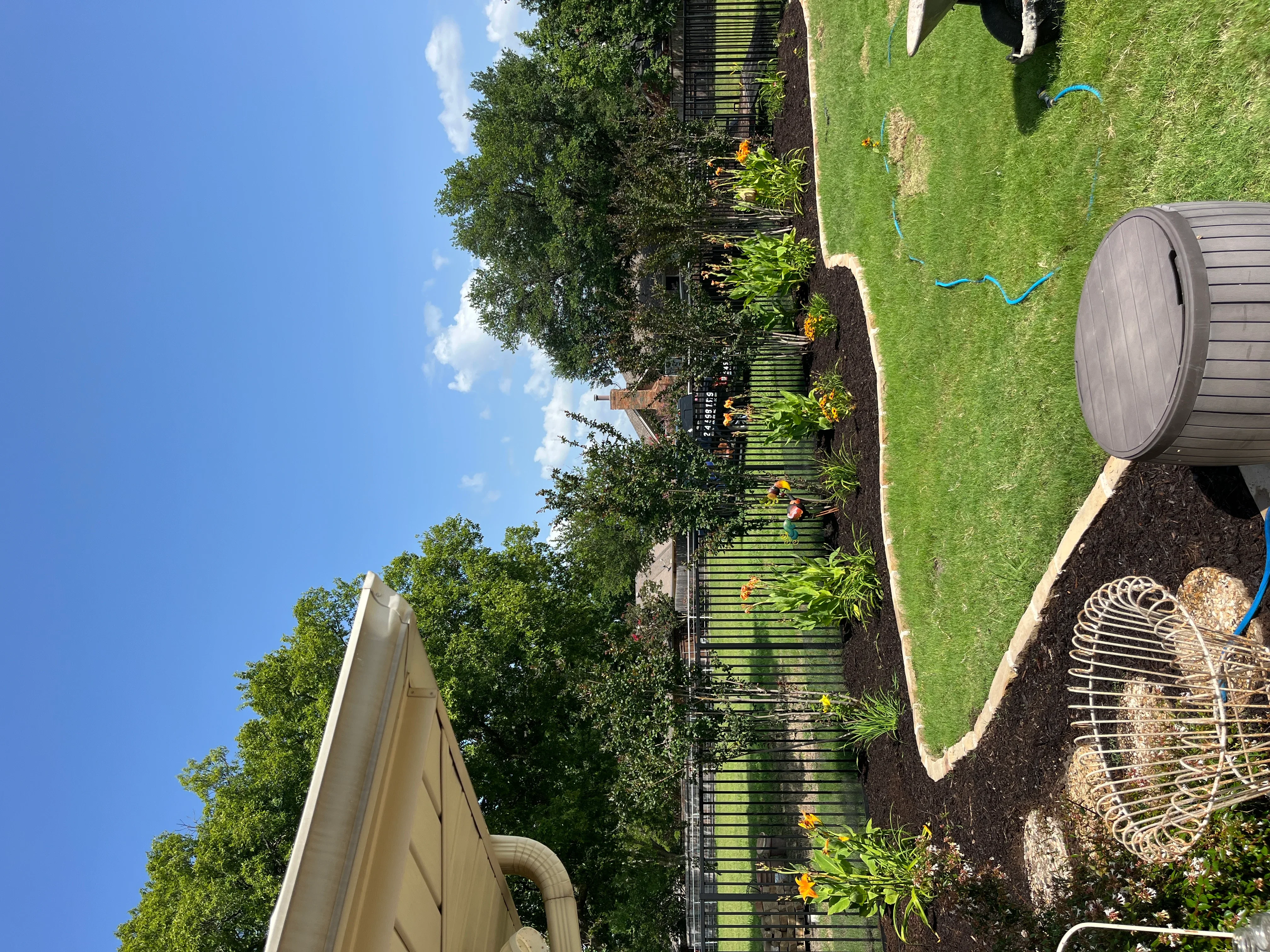 Newly installed landscape beds with mulch, flowering perennials, lawn, and rain barrel system