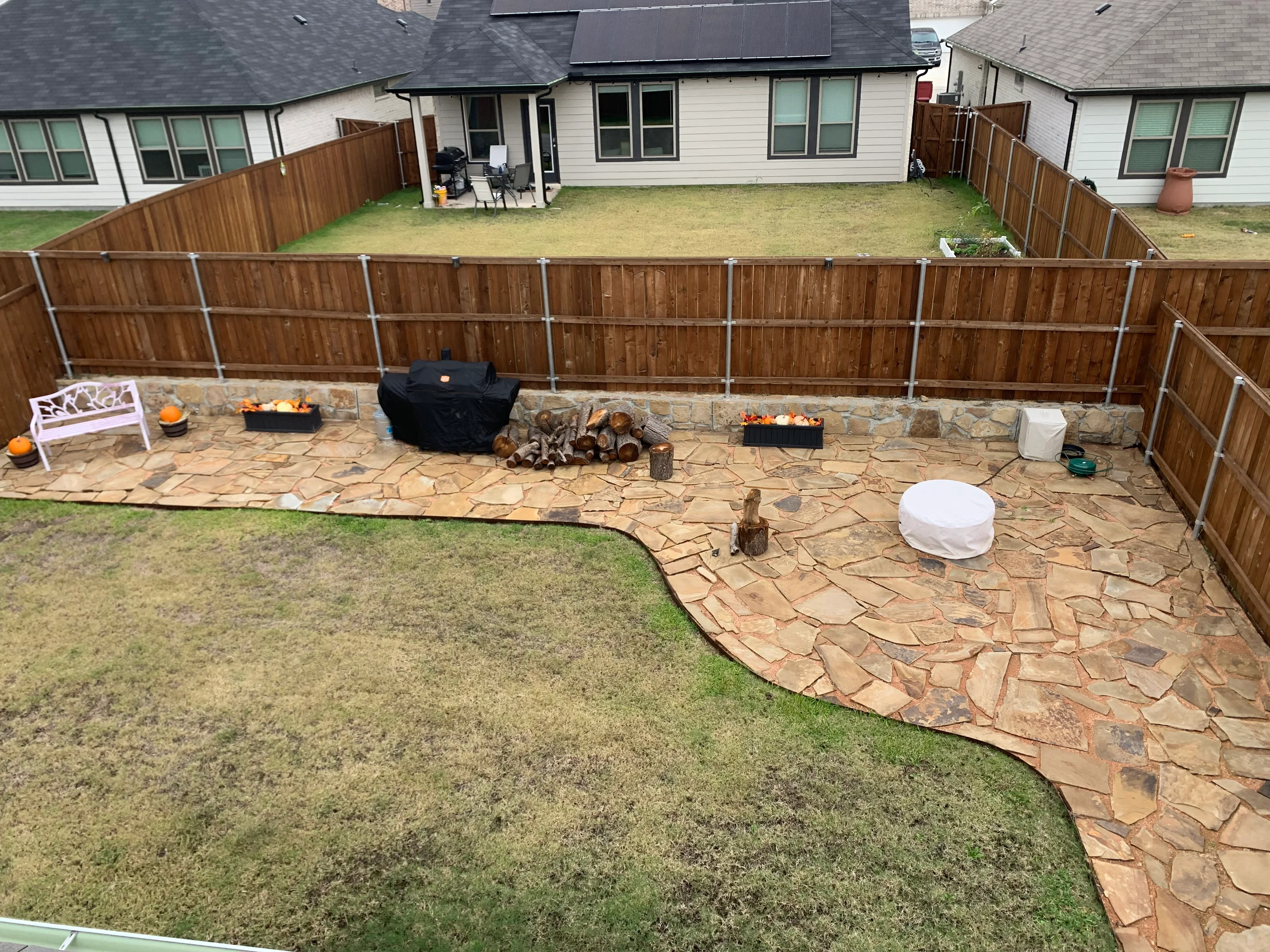 Flagstone patio with irregular stone pavers and new wood privacy fence with metal posts