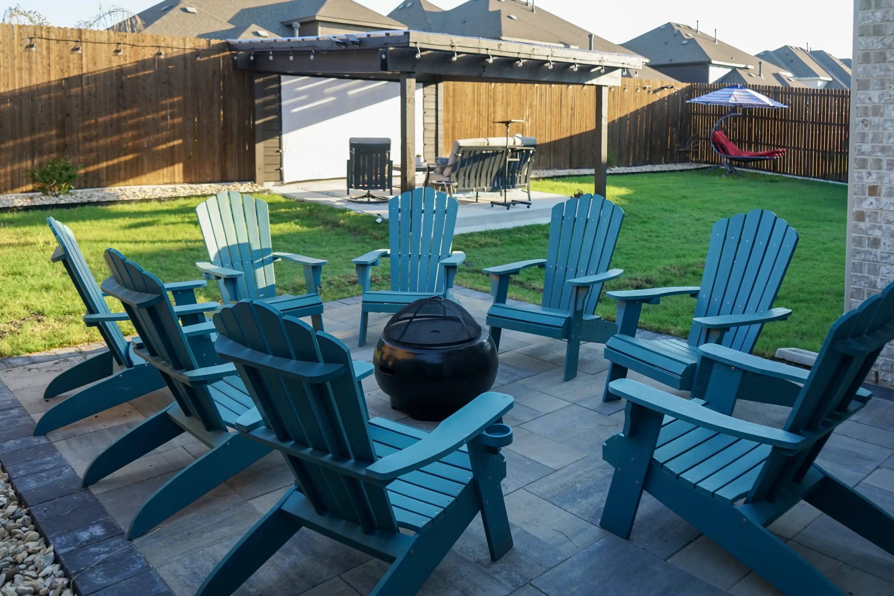 Paver patio with fire pit, Adirondack seating, pergola, and privacy fencing